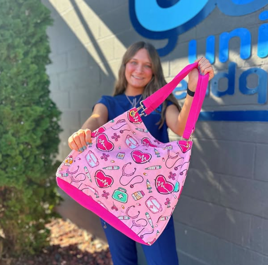 Person holding a pink bag with medical-themed design in front of a store sign.