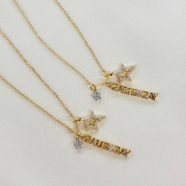 Two gold necklaces with star and 'GAME DAY' pendants on a light background